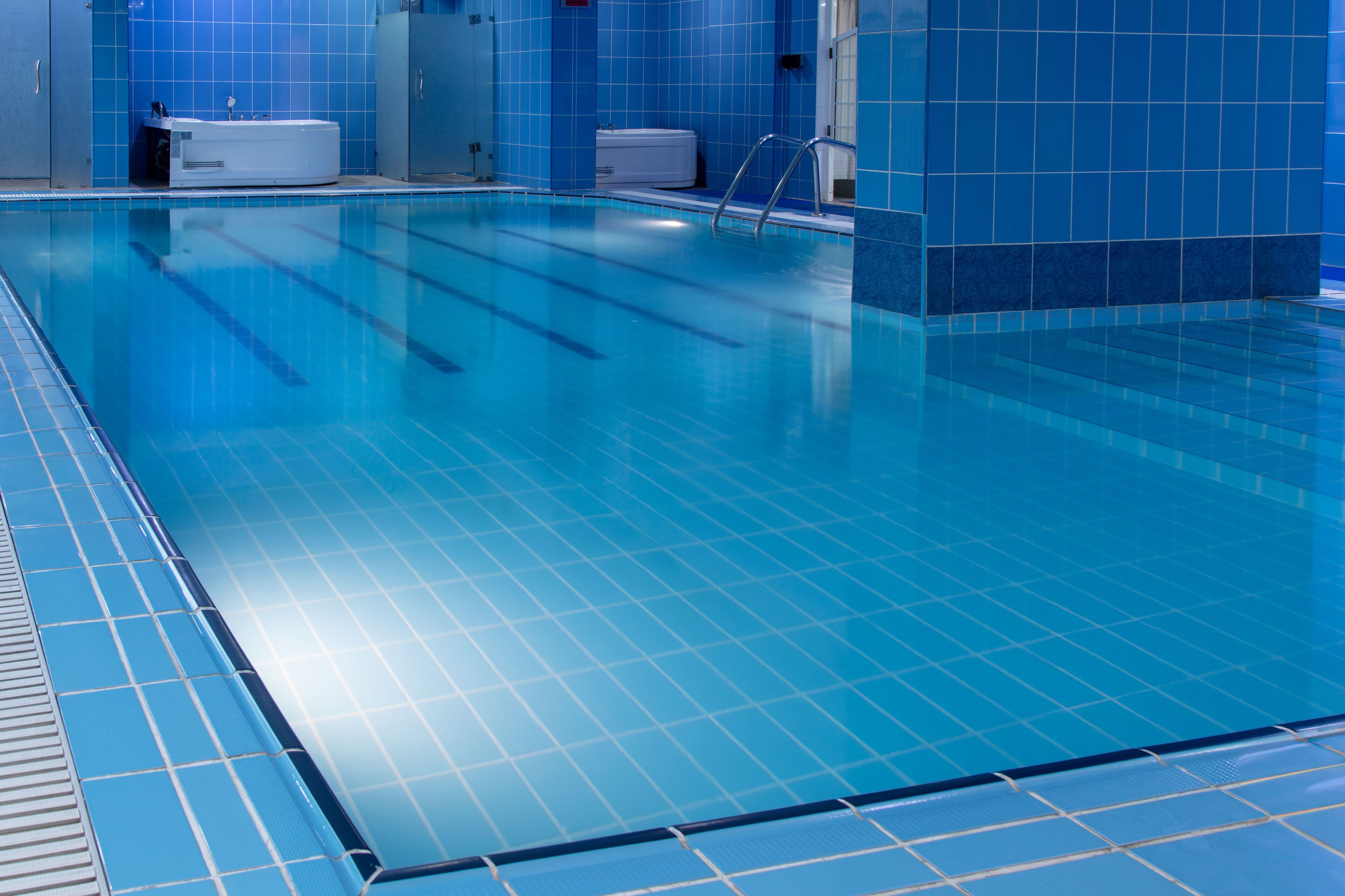 A swimming pool with blue tiles and a tiled deck.