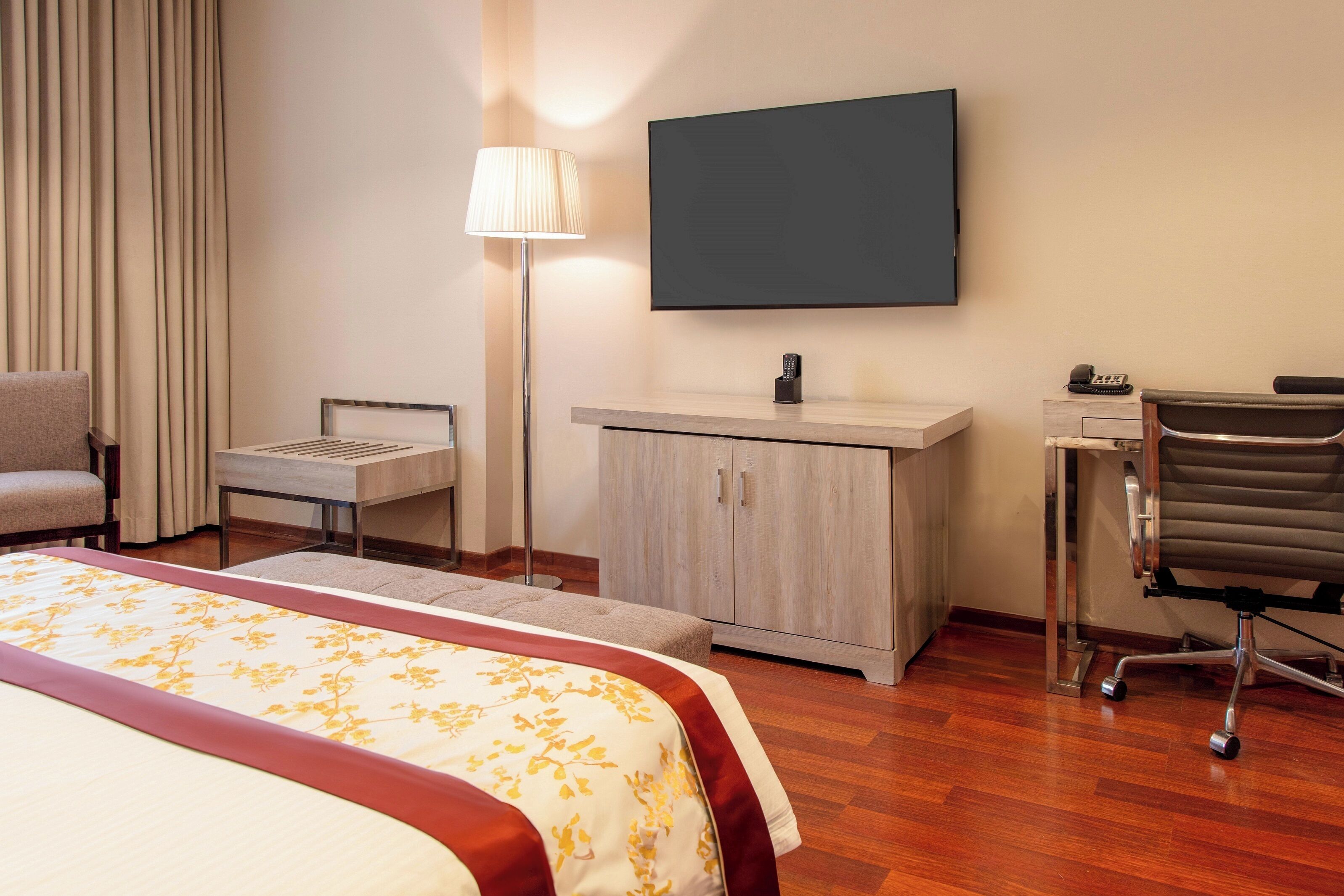 Ein Hotelzimmer mit Bett, Schreibtisch, Stuhl, Fernseher und Kleiderschrank.
