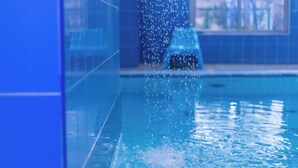 Ein Schwimmbecken mit klarem Wasser und sichtbaren Blasen, umgeben von blauen Fliesenwänden.