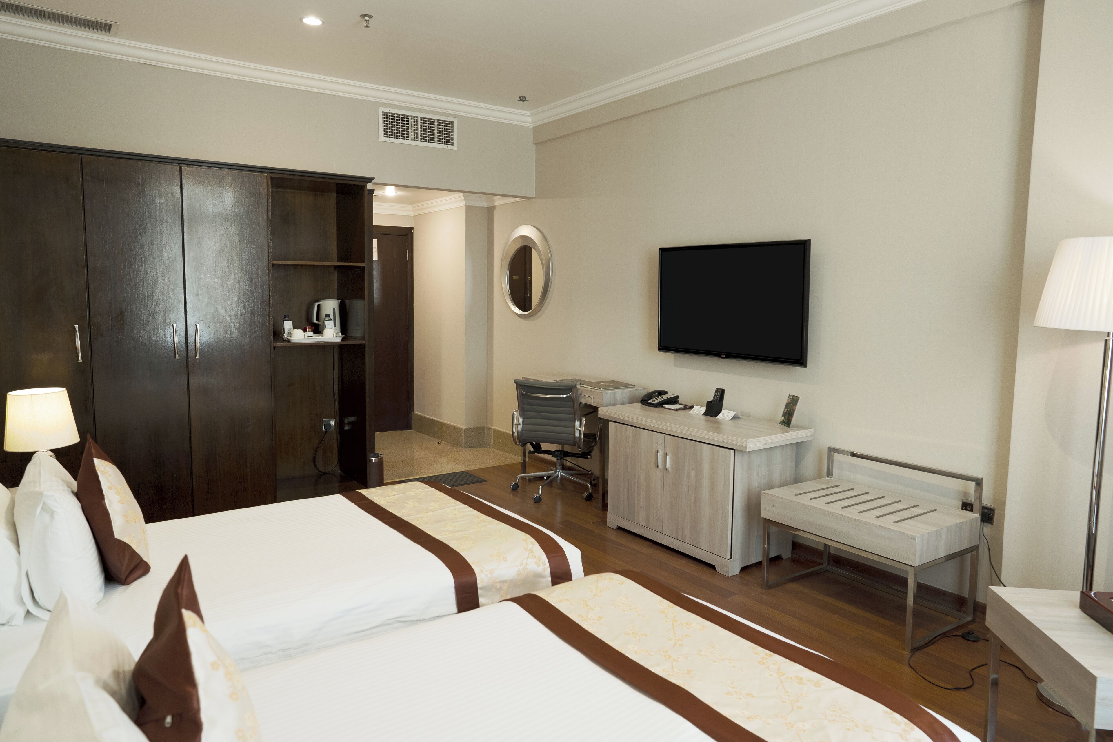 A hotel room with two beds, a desk, a TV, and a wardrobe.