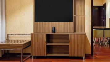 A modern entertainment unit with a flat-screen TV, wooden finish, and built-in shelves.