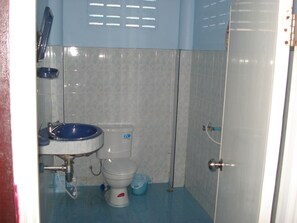 A small bathroom with a toilet, sink, and shower.