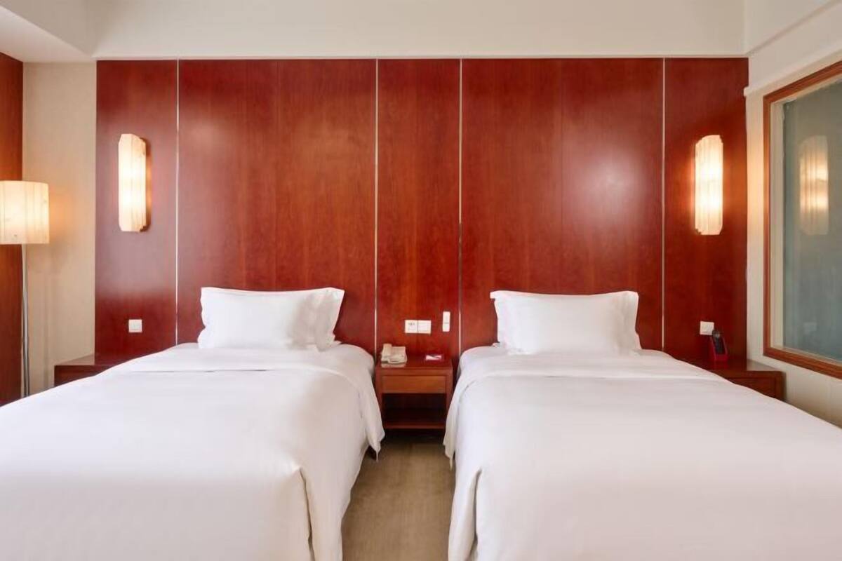 Une chambre d’hôtel avec deux lits, des murs lambrés, des lampes de chevet et une table de chevet avec un téléphone.