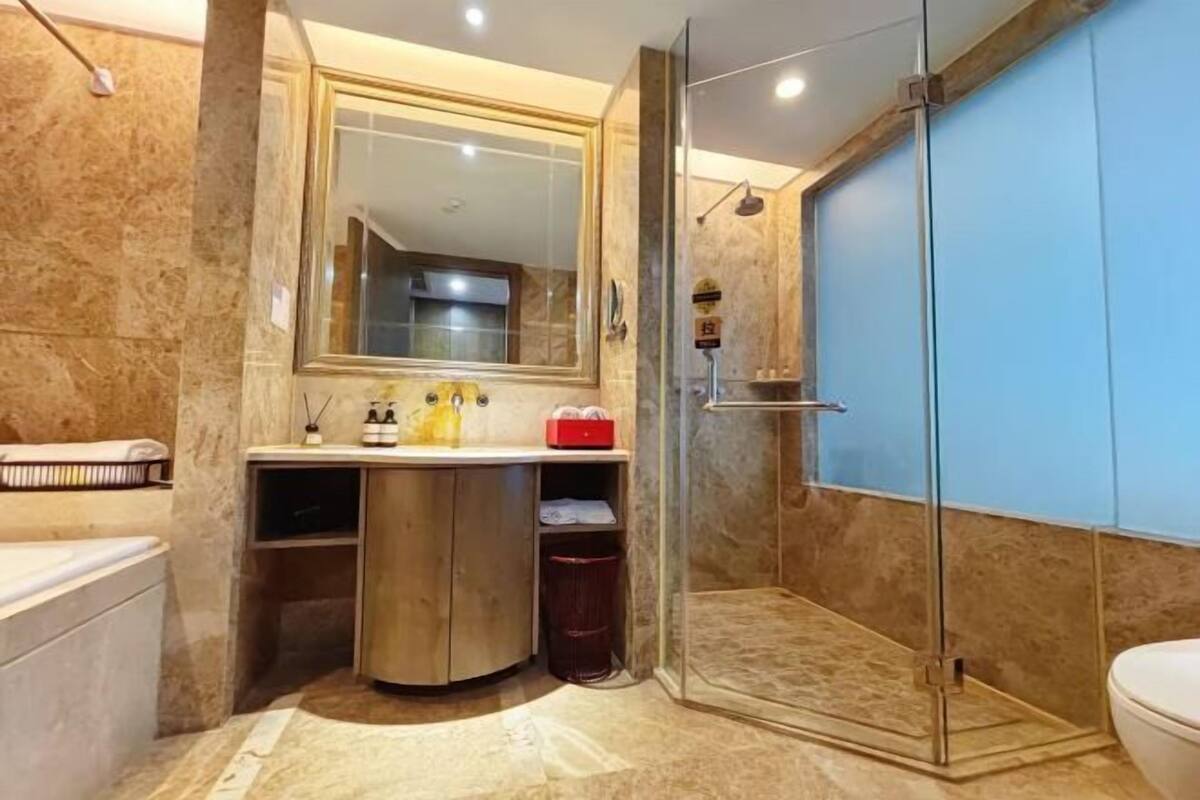 Une salle de bain avec une douche à parois de verre, un lavabo avec un miroir au-dessus et des toilettes.