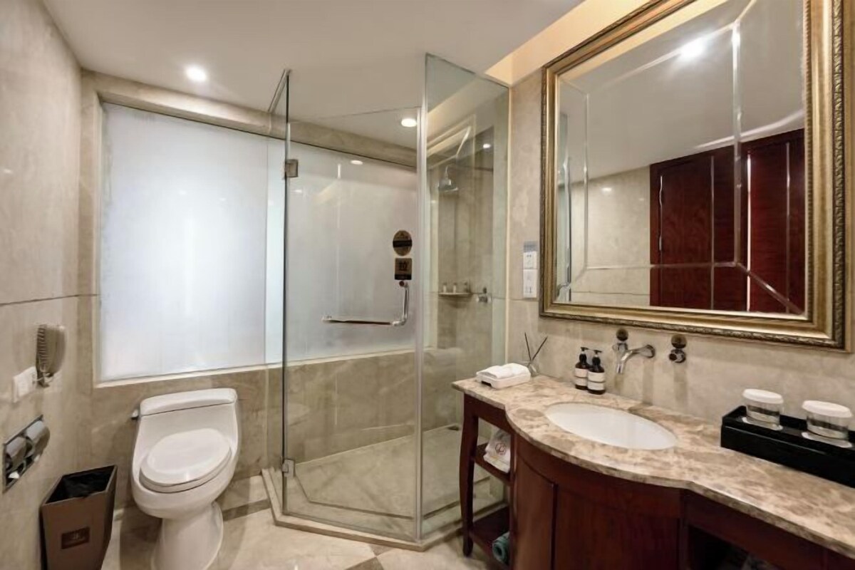 A modern bathroom with a glass-enclosed shower, a white toilet, and a vanity with a large mirror.