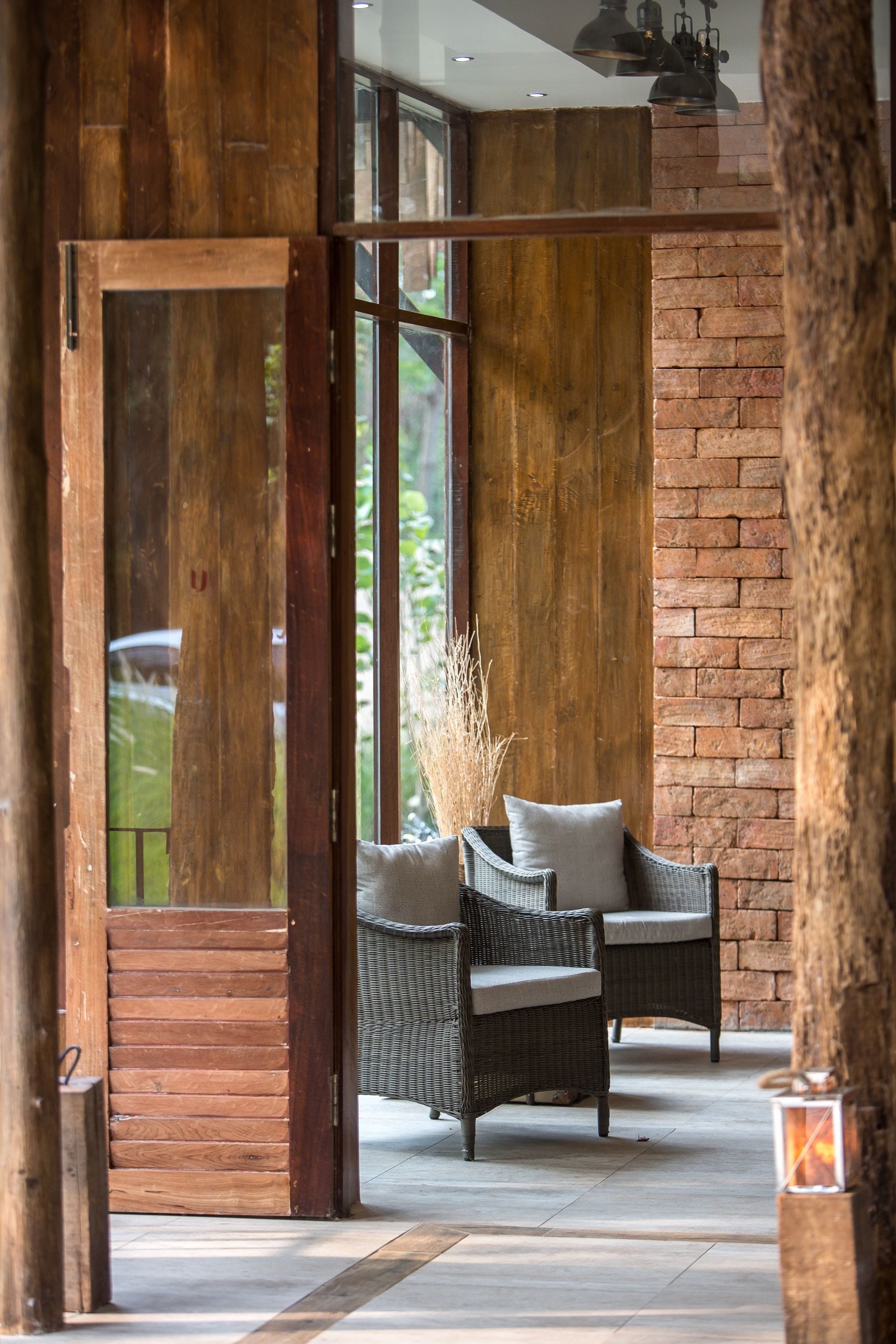 A modern interior with wicker furniture, a brick wall, and a large wooden door.