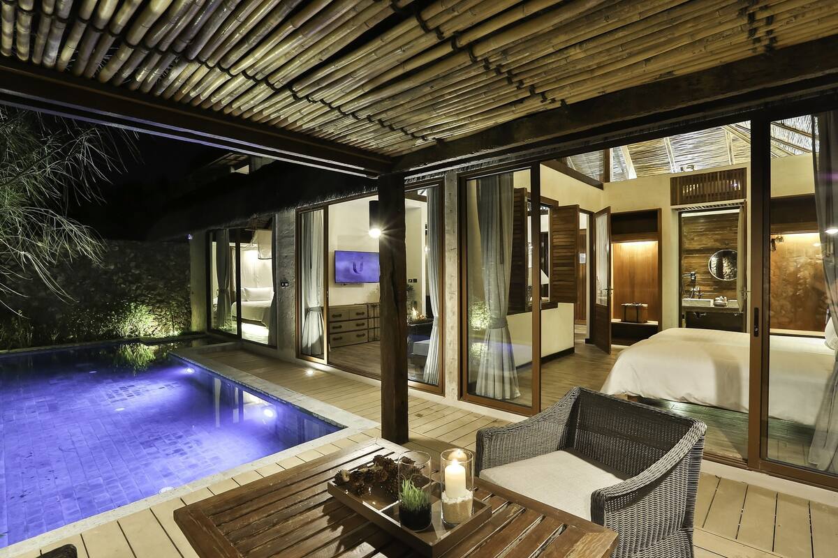 A modern hotel room with a glass door leading to a private balcony with a pool.