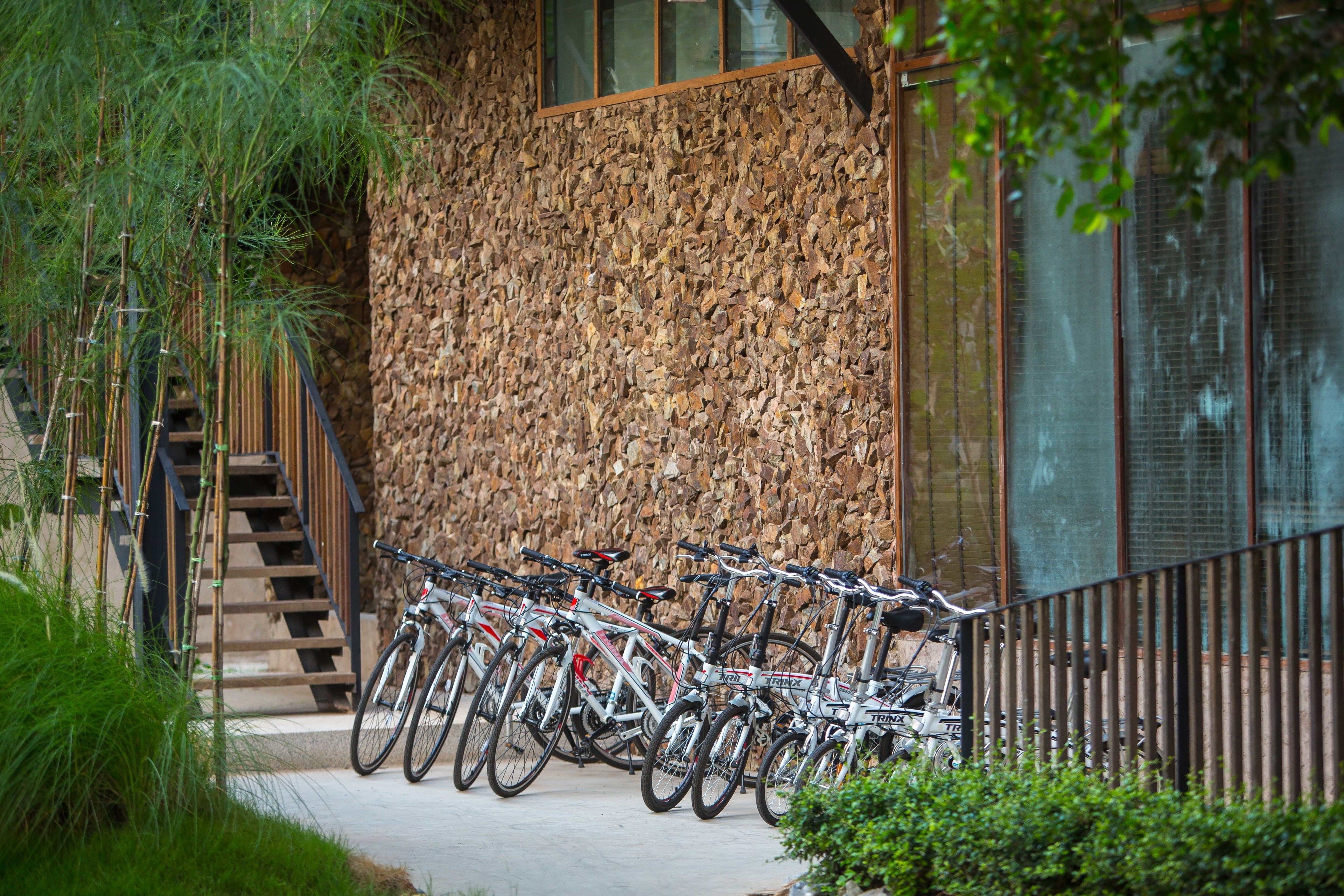Des vélos sont garés devant un bâtiment dont la façade est recouverte de bois et qui possède un escalier.