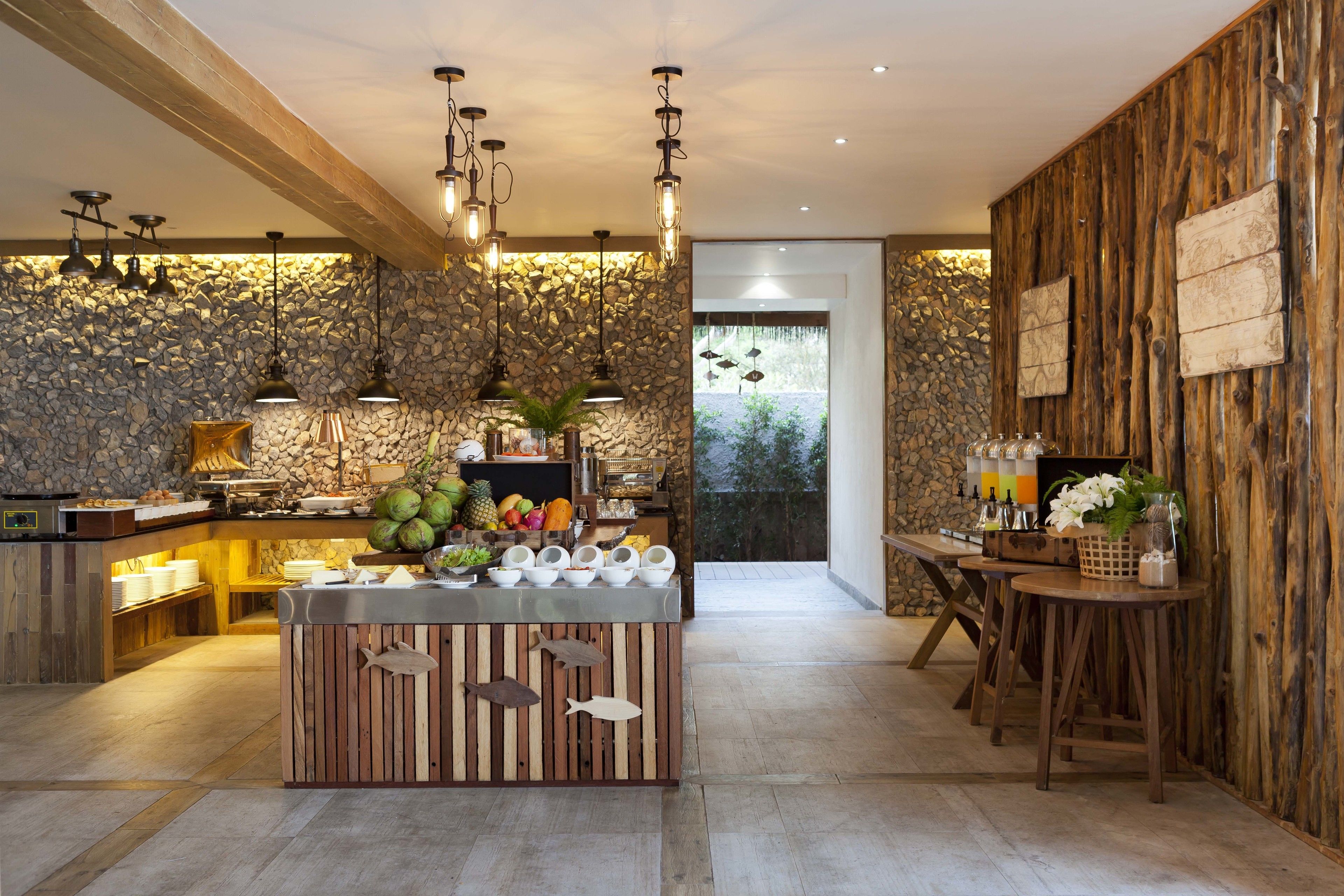 A modern kitchen with a central island, stone wall, wooden accents, and pendant lighting.