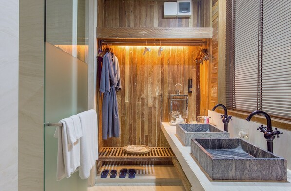 A modern bathroom with a wooden wall, a glass shower enclosure, and a vanity with two sinks. - U Pattaya (Sattahip)