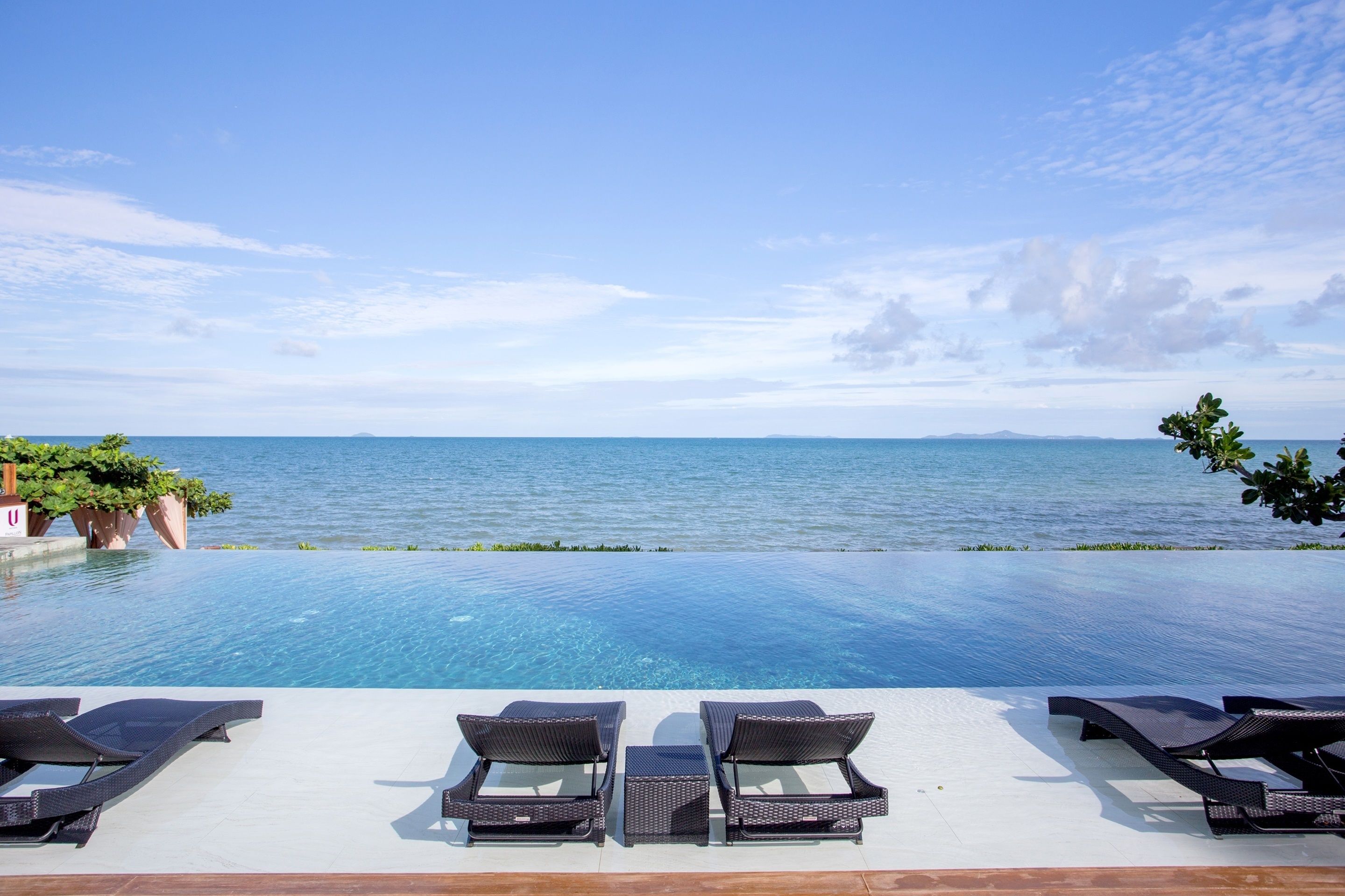 An infinity pool with lounge chairs facing the sea.