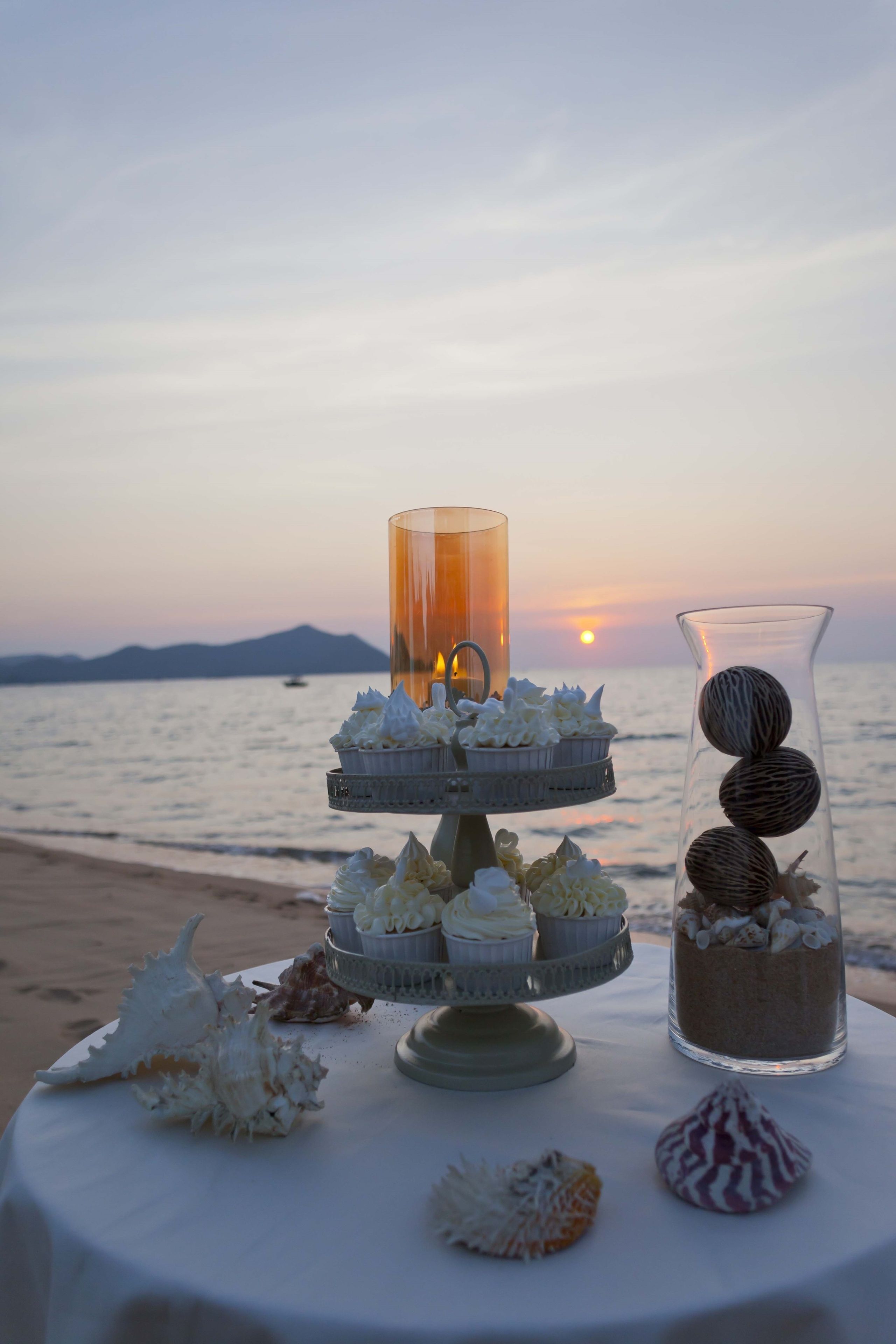 A dessert table with a sunset view on a beach.