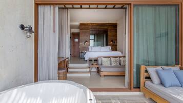 Una habitación de hotel moderna con una cama grande, un sofá y una bañera.