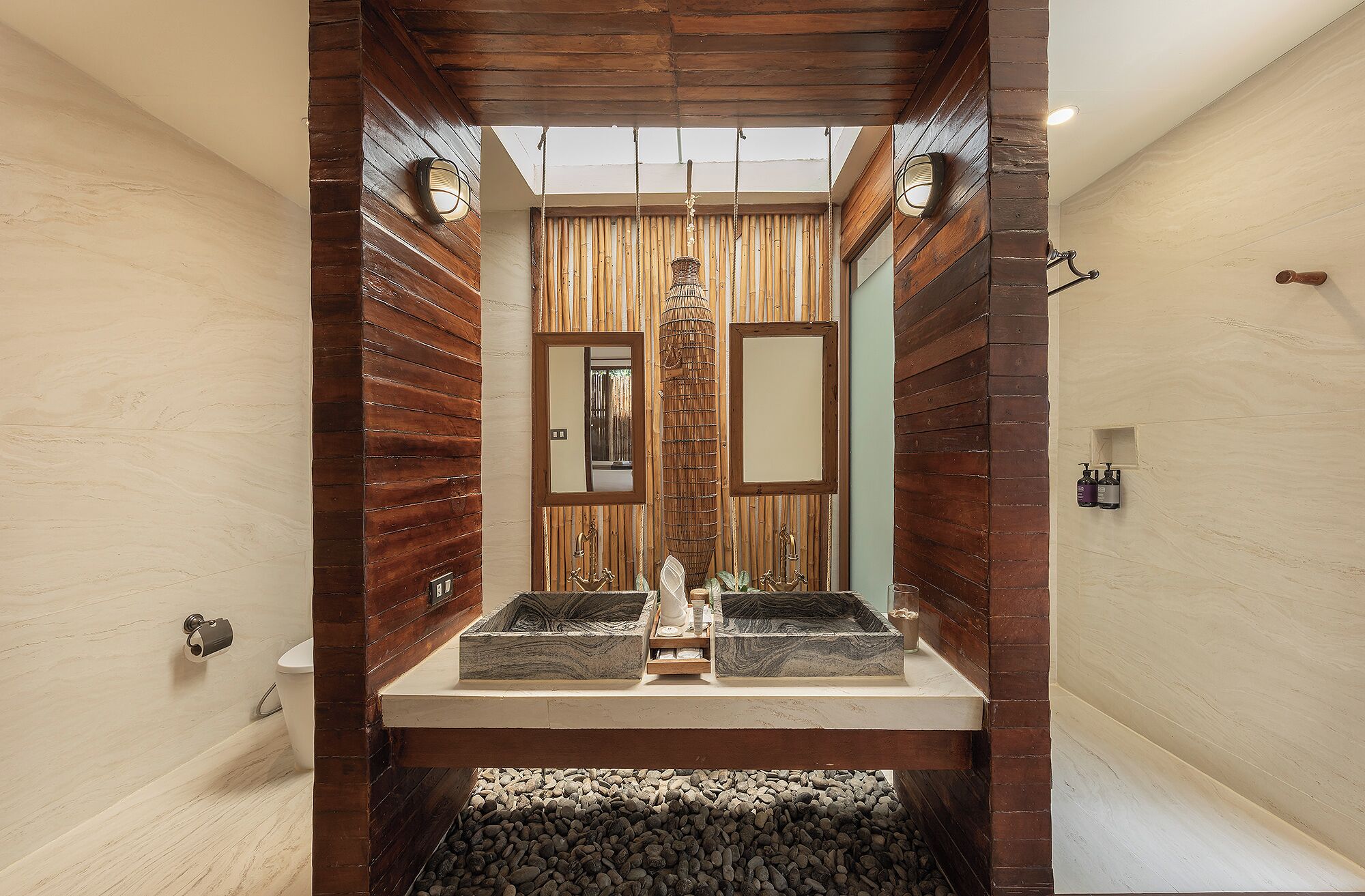A bathroom with a wooden wall design, a central sink with granite countertop, and a hanging light fixture.