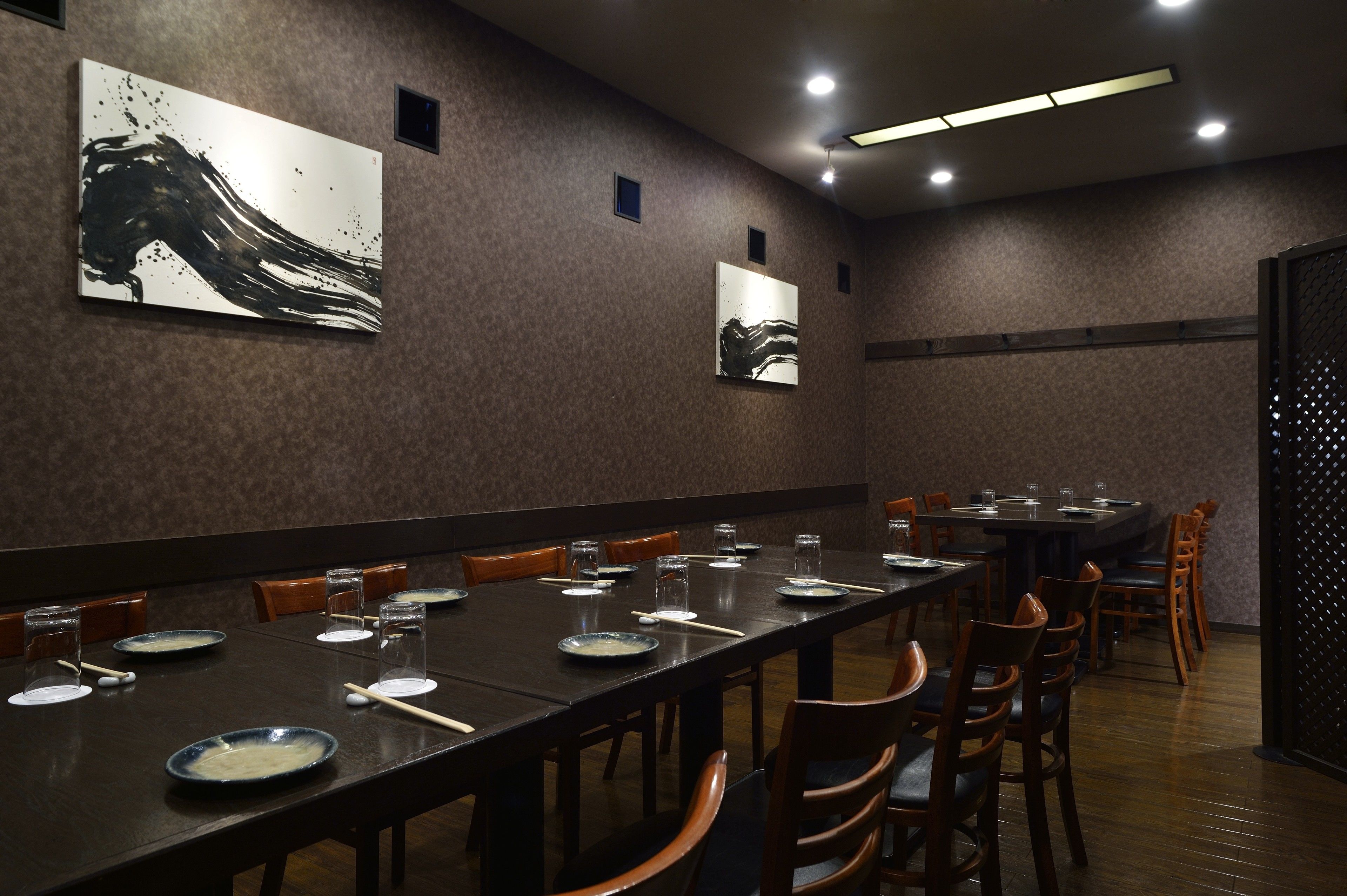 A conference room with long tables, chairs, and artwork on the walls.