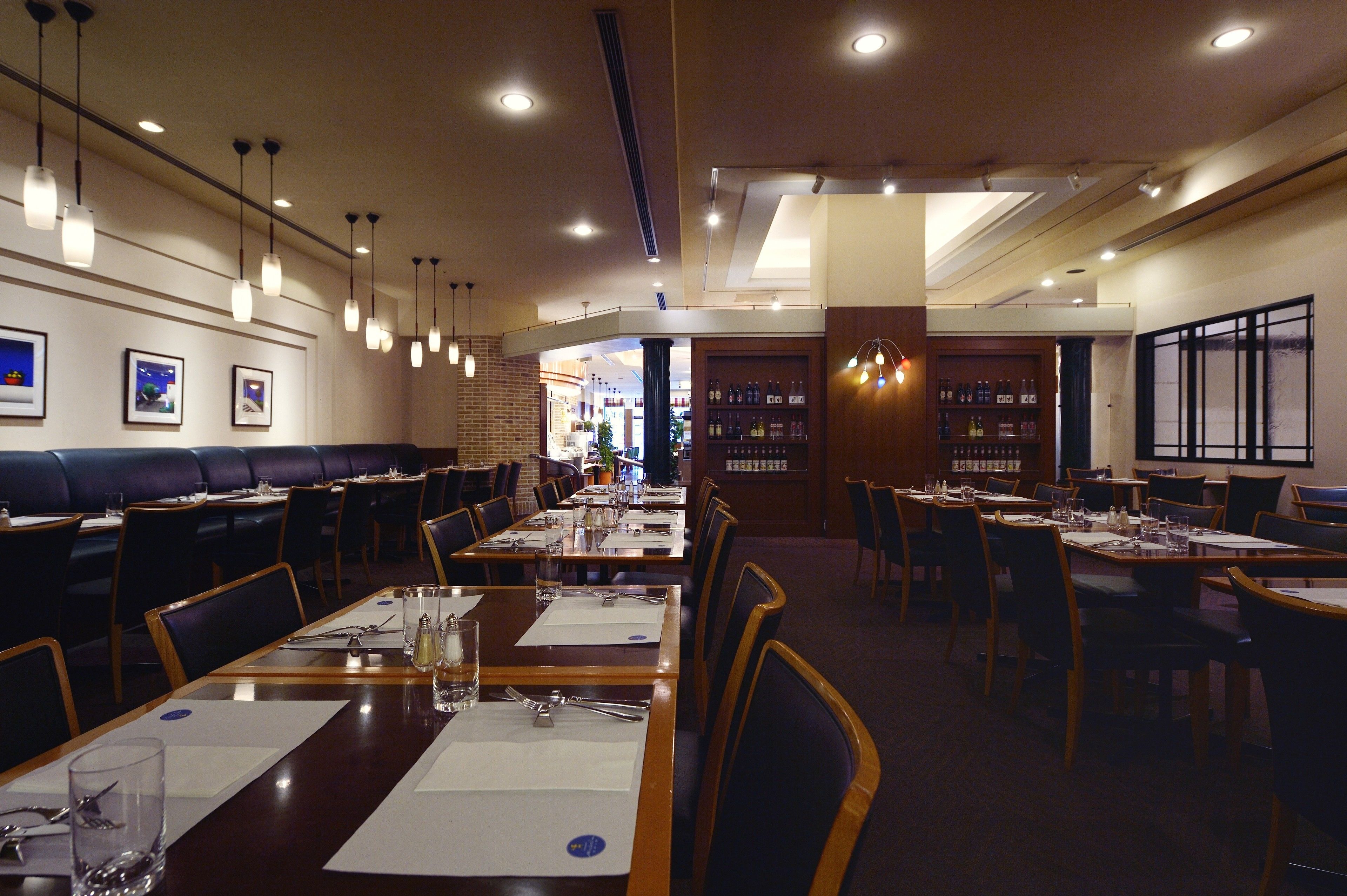 A restaurant with multiple dining tables and booths, overhead lighting, and framed pictures on the walls.