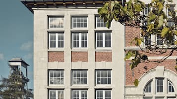 A multi-story building with a mix of brick and stone facade, multiple windows, and a bell tower.