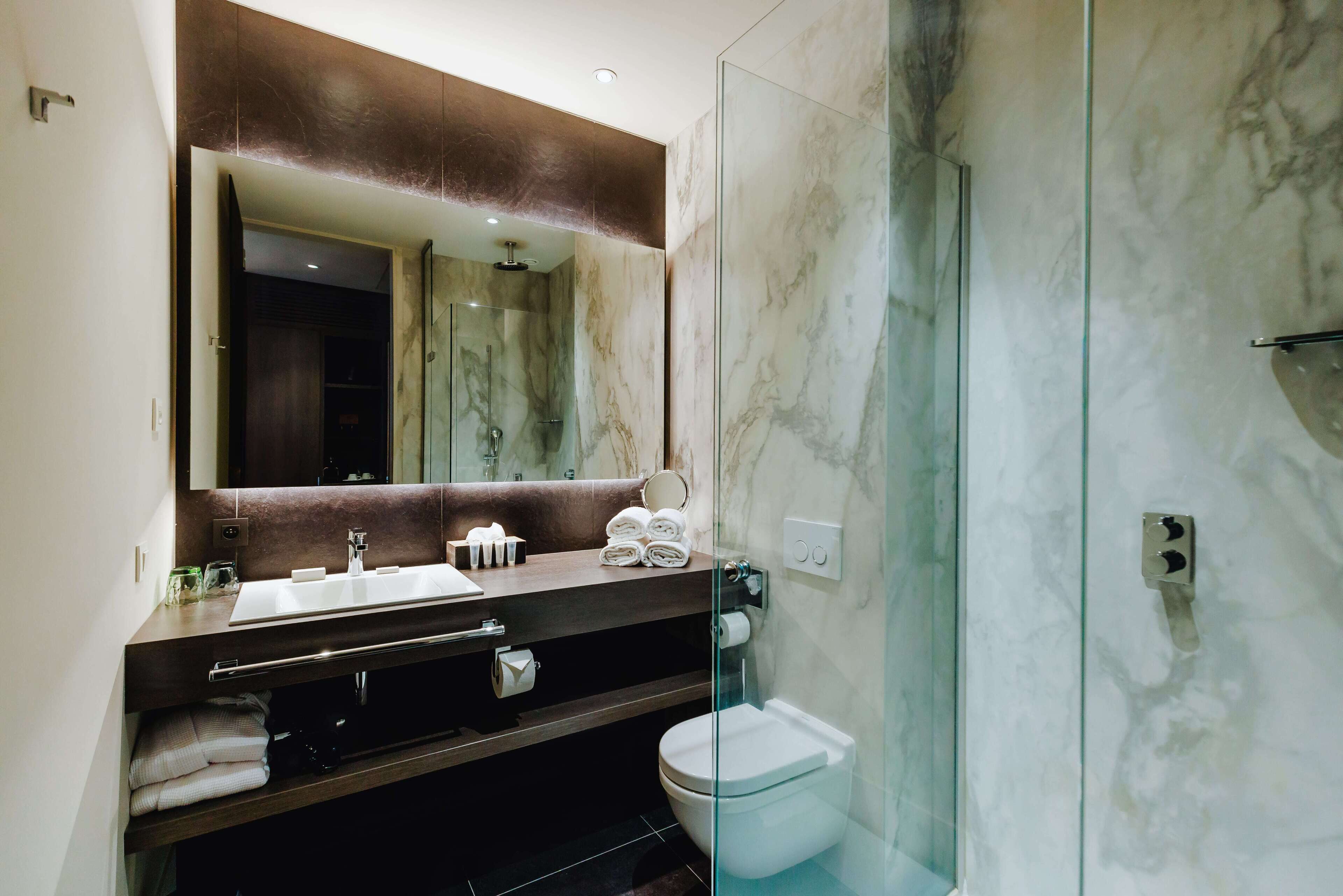 Une salle de bain moderne avec un meuble-lavabo en marbre, une cabine de douche en verre et des toilettes.