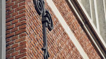 A close-up of a black metal sign with a unique design, mounted on a brick wall.