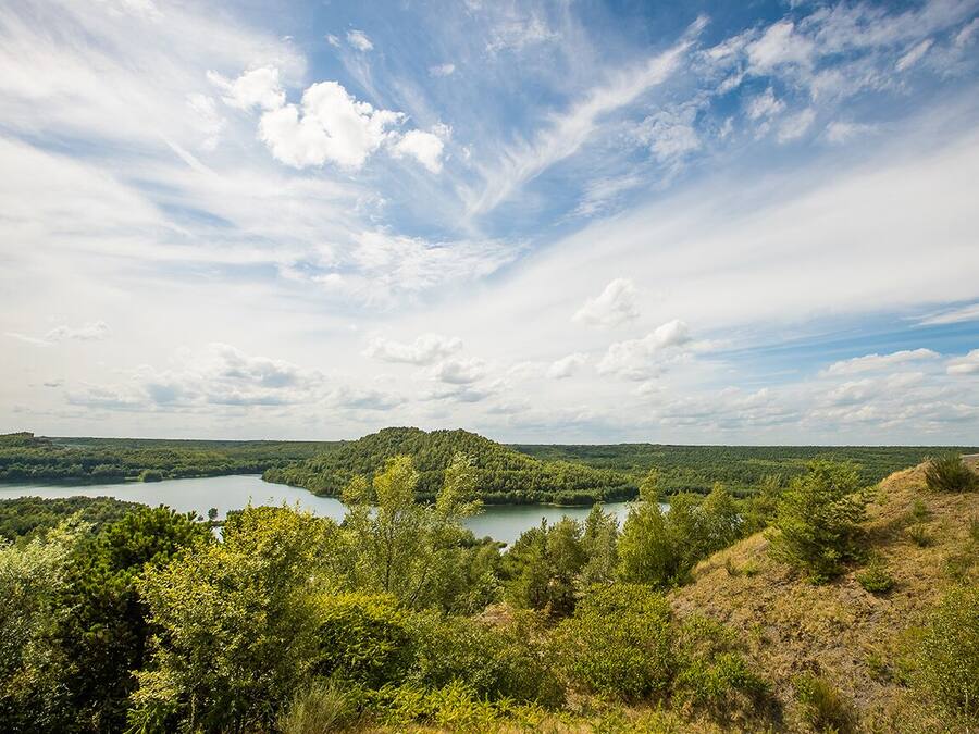 A natural landscape with a lake, forested hills, and a clear sky.
