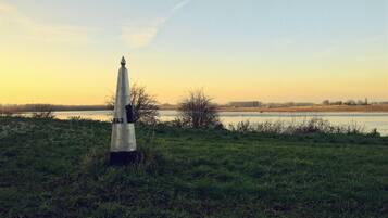 A grassy field with a monument in the foreground and a body of water in the background.