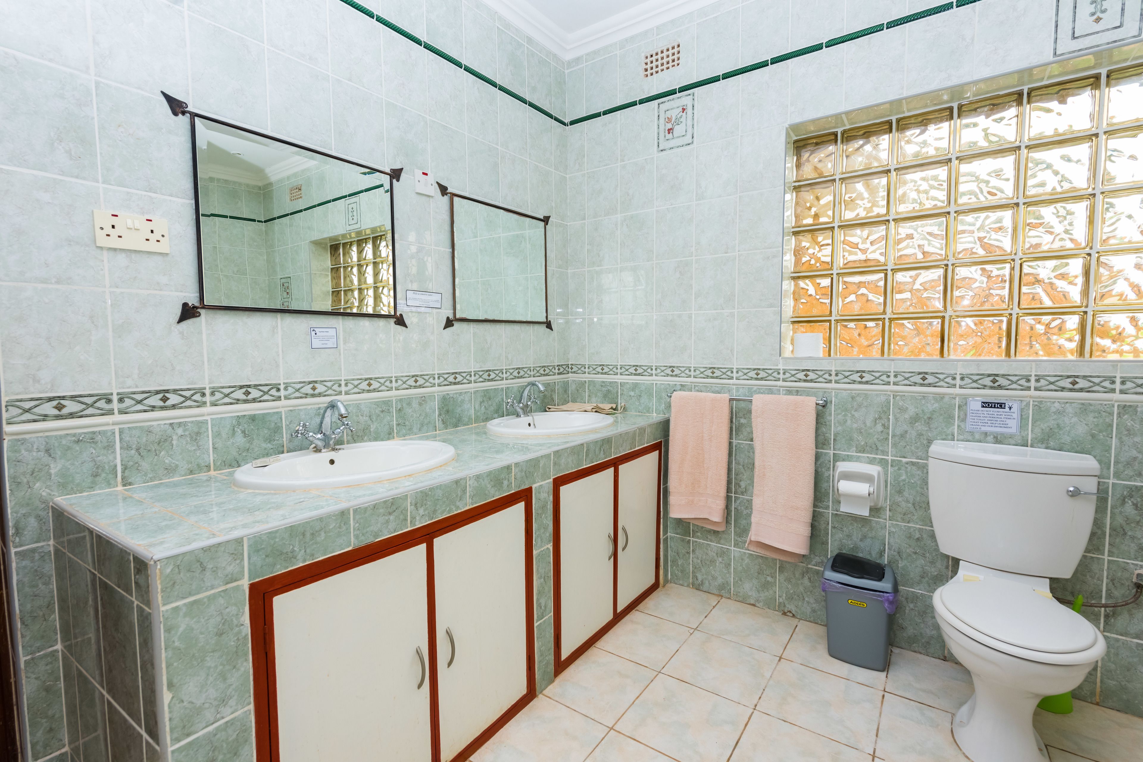 A bathroom with two sinks, a toilet, and a window with a decorative grid pattern.