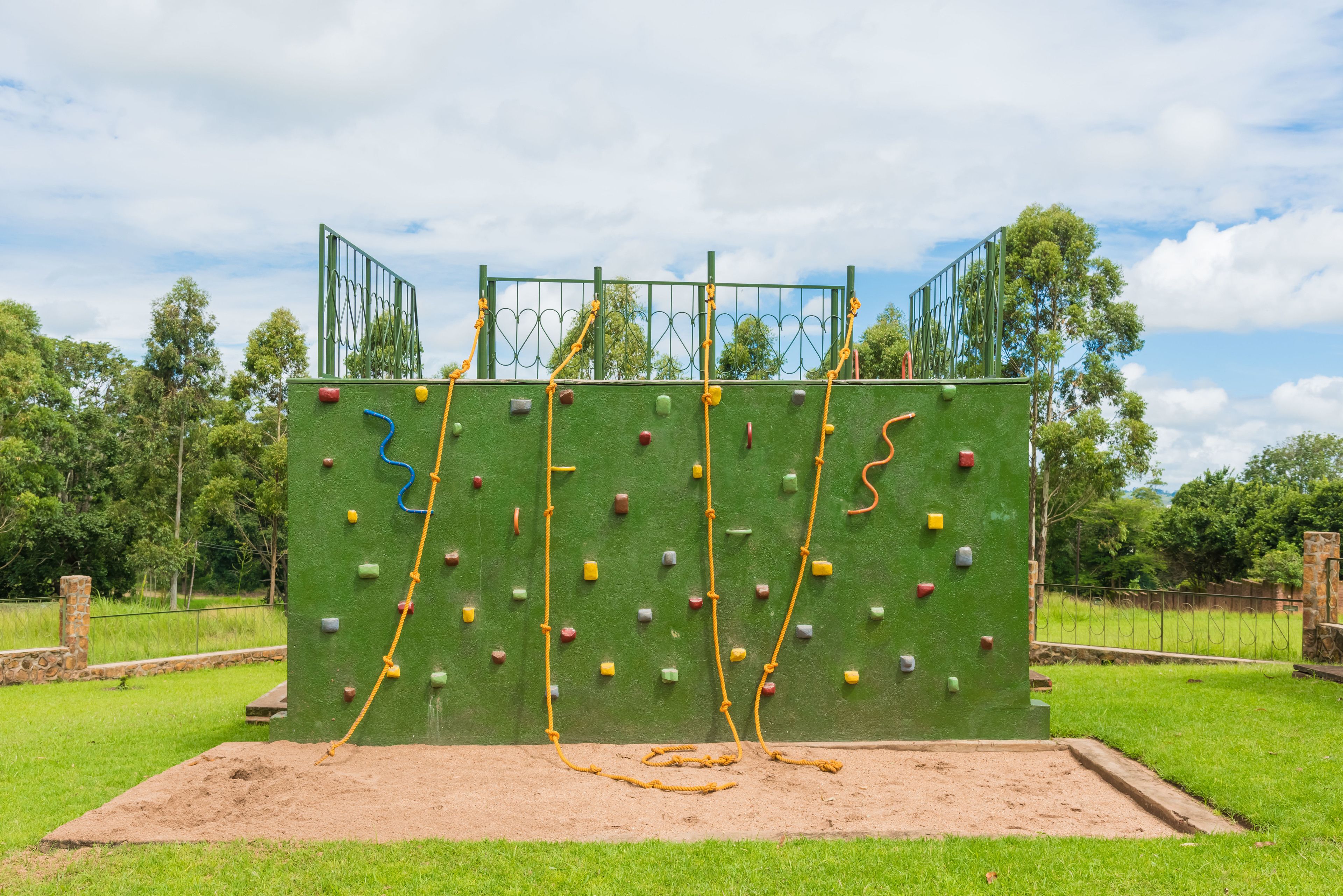 A rock climbing wall with various colored holds and a rope.