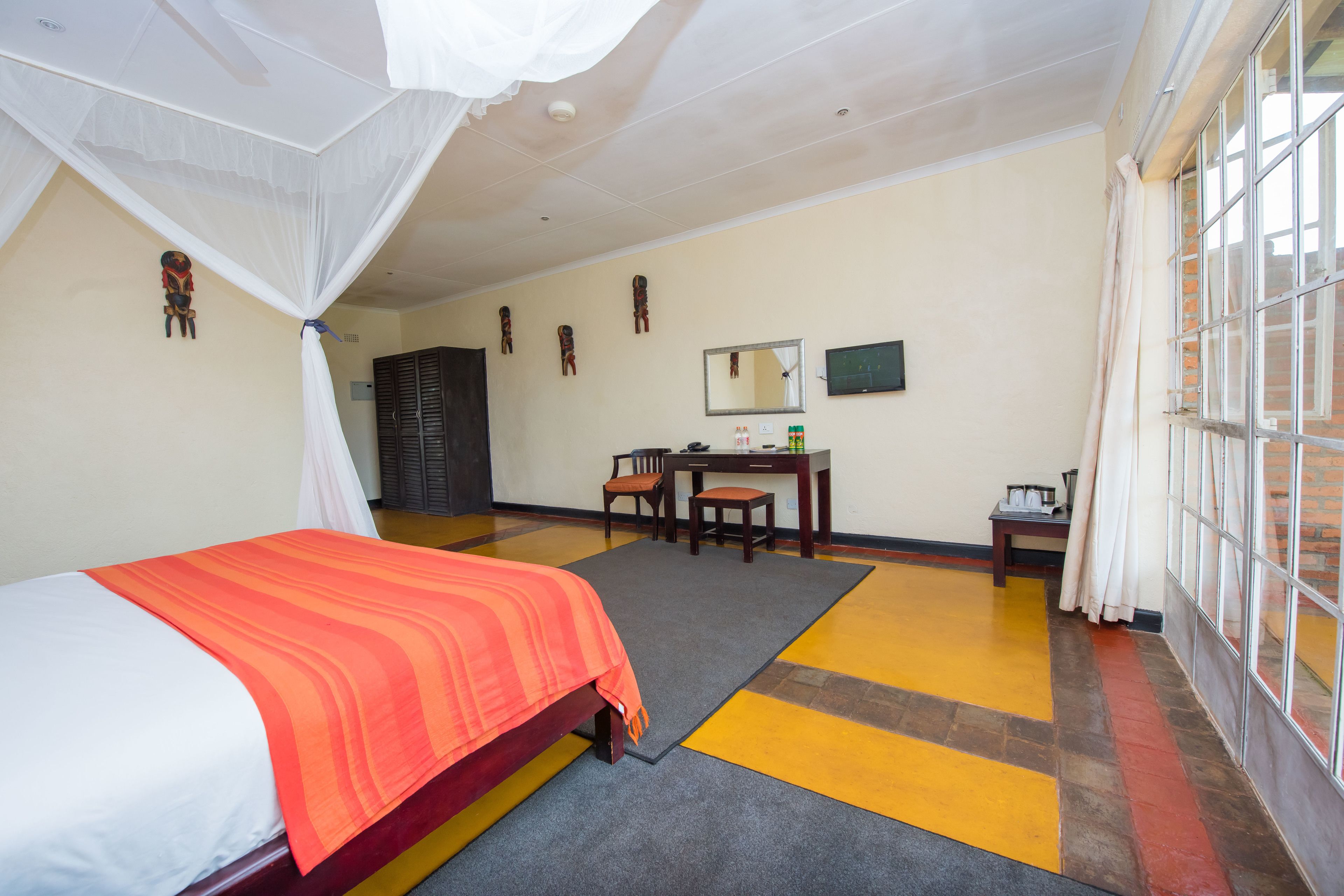 Ein Hotelzimmer mit Bett, Schreibtisch, Stuhl und einem großen Fenster.