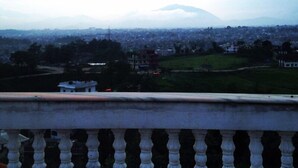 A balcony with a view of a cityscape and a mountain in the distance.