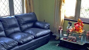 A black leather sofa in a room with a glass table displaying a statue and a small vase.