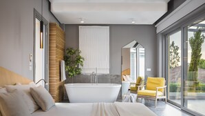 Une chambre moderne avec un grand lit, une baignoire et un balcon offrant une vue agréable.