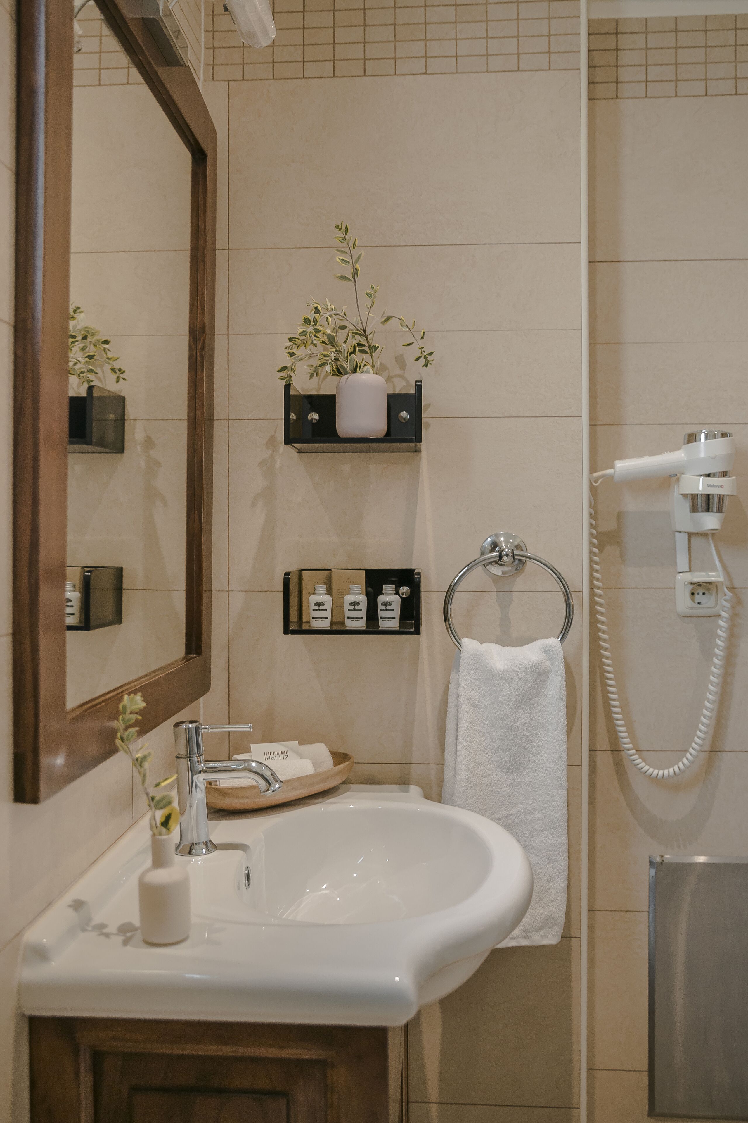 A bathroom with a sink, mirror, towel rack, and a hairdryer.
