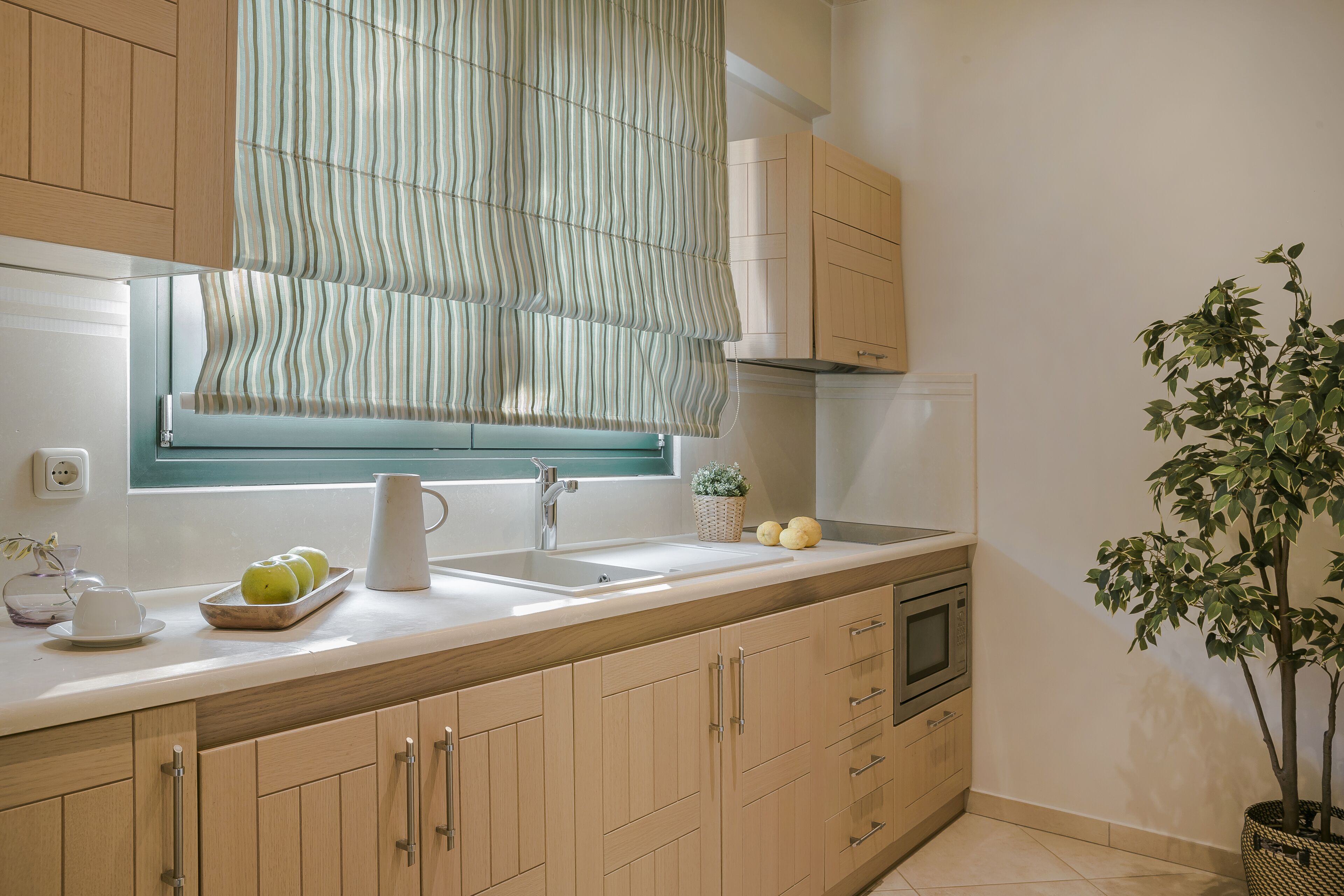 A kitchen with wooden cabinets, a sink, a microwave, and a potted plant.