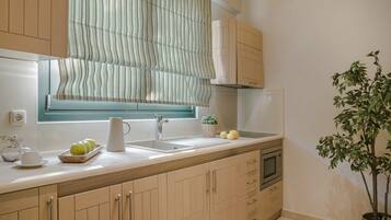 A kitchen with wooden cabinets, a sink, a microwave, and a potted plant.
