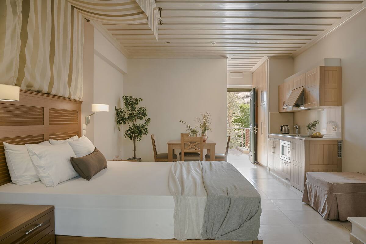 A bedroom with a bed, bedside table, and a view of a dining area with a table and chairs.