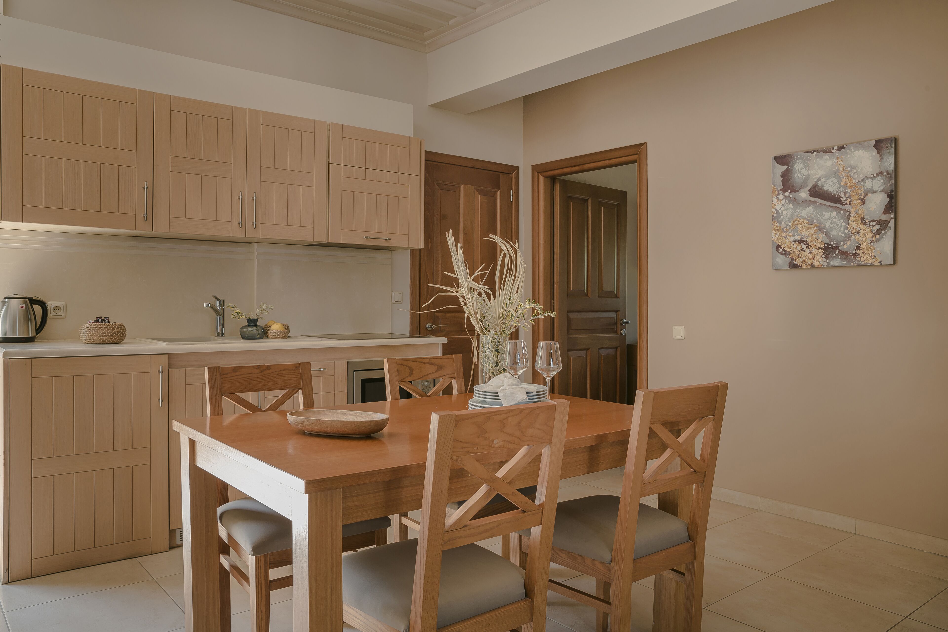 Una cocina moderna con armarios de madera, una mesa de comedor con sillas y un florero con ramas.
