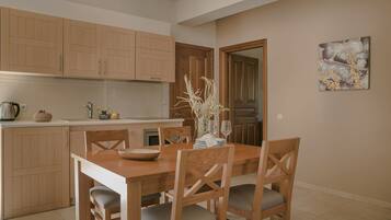 Una cocina moderna con armarios de madera, una mesa de comedor con sillas y un florero con ramas.