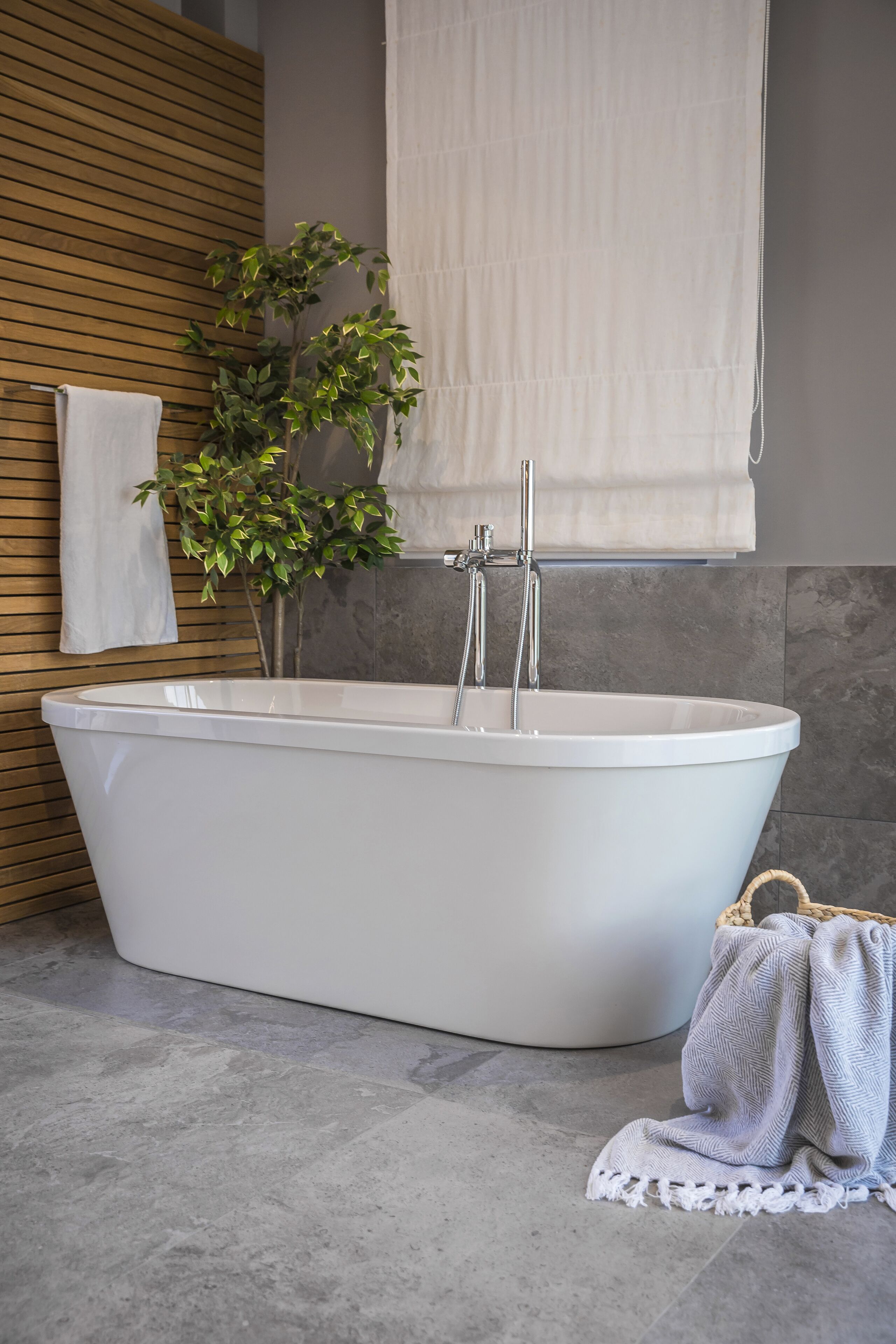 Une salle de bain moderne avec une baignoire sur pieds, un mur recouvert de panneaux en bois, une plante en pot et un porte-serviettes.
