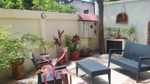 Un patio con mobiliario exterior, plantas en macetas y un letrero colgado en la pared.