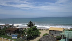 A coastal view with a beach, houses, and a clear sky. - Puerta Sol Inn (Manglaralto)