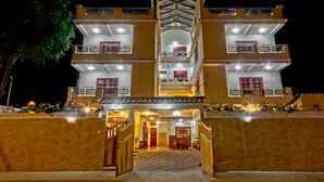 A multi-story hotel with a central entrance, balconies on each floor, and a well-lit facade. - Puerta Sol Inn (Manglaralto)