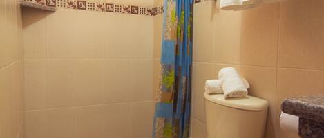Un baño con inodoro, cortina de ducha, toallero y una ventana pequeña.