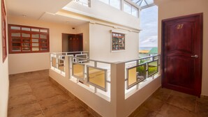 A spacious interior with a balcony, a wooden door marked with the number 27, and a view of the sky through the windows. - Puerta Sol Inn (Manglaralto)
