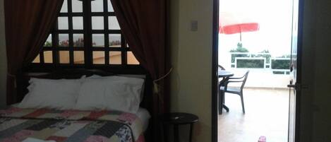 Un dormitorio con cama, cortinas y vistas a un espacio exterior con mesa y sillas.