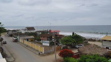 Un pueblo costero con una calle bordeada de casas, una playa y el océano al fondo.
