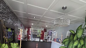 Aula, jossa on kuvioitu matto, ruukkukasveja, vastaanottotiski ja kattokruunu.