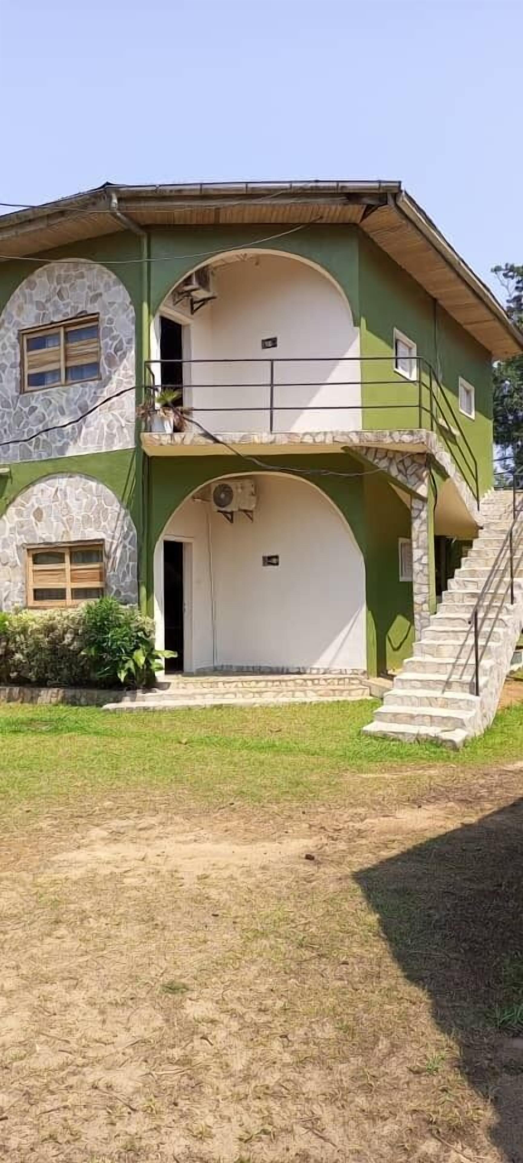 A two-story house with a stone facade, a white door, and a staircase leading to the upper floor.