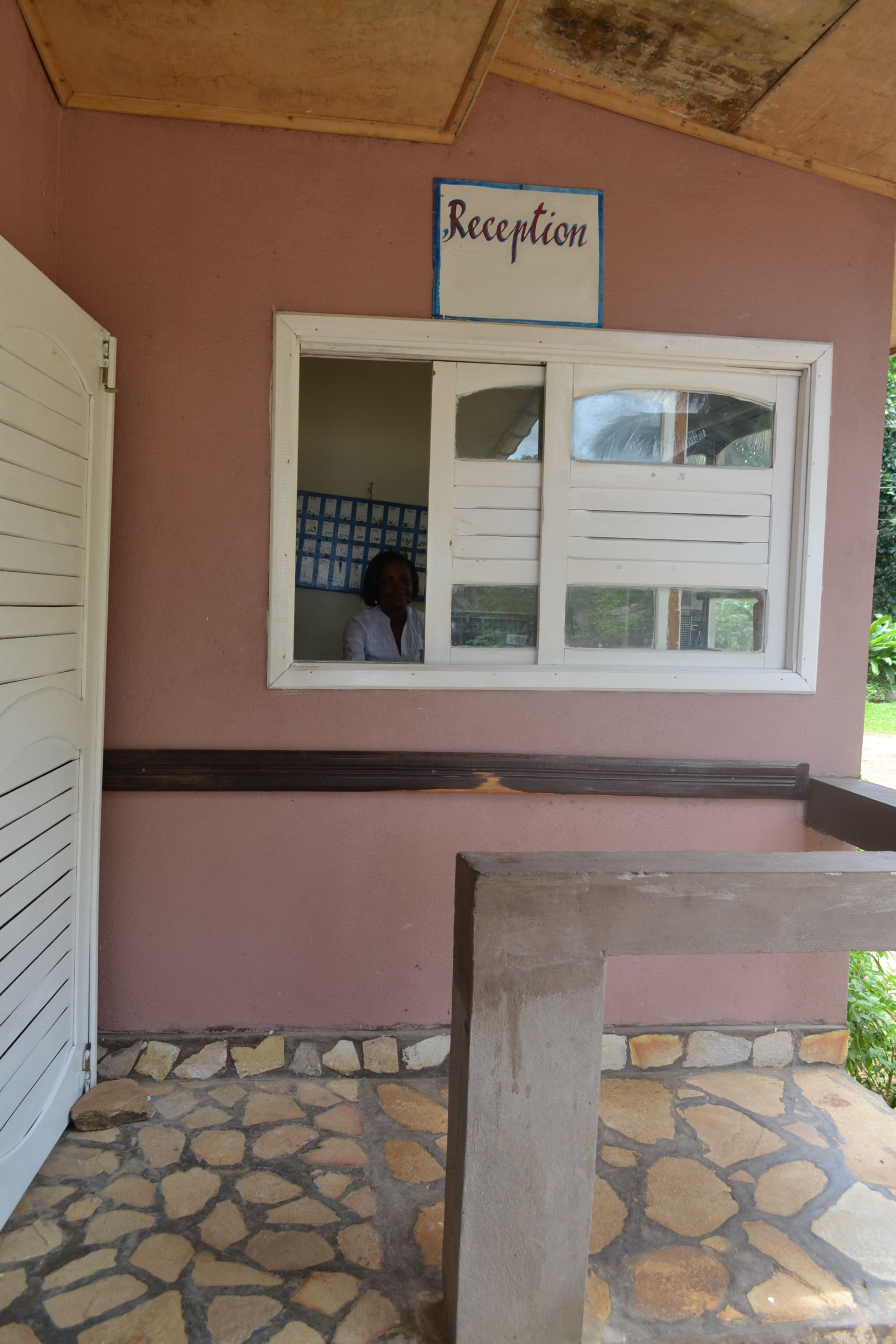Un'area reception con un cartello, una finestra con tende e un pavimento in pietra.