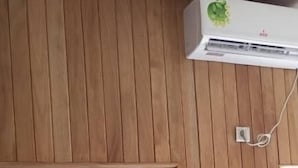 Una habitación con paneles de madera en las paredes, una puerta blanca y un equipo de aire acondicionado instalado en la pared.