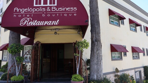 Ein Boutique-Hotel namens Angelópolis & Business mit einem maroonfarbenen Vordach und einem Schild über dem Eingang.
